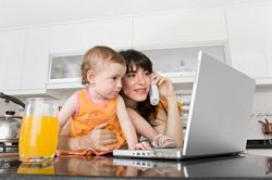 mother with baby and laptop in kitchen
